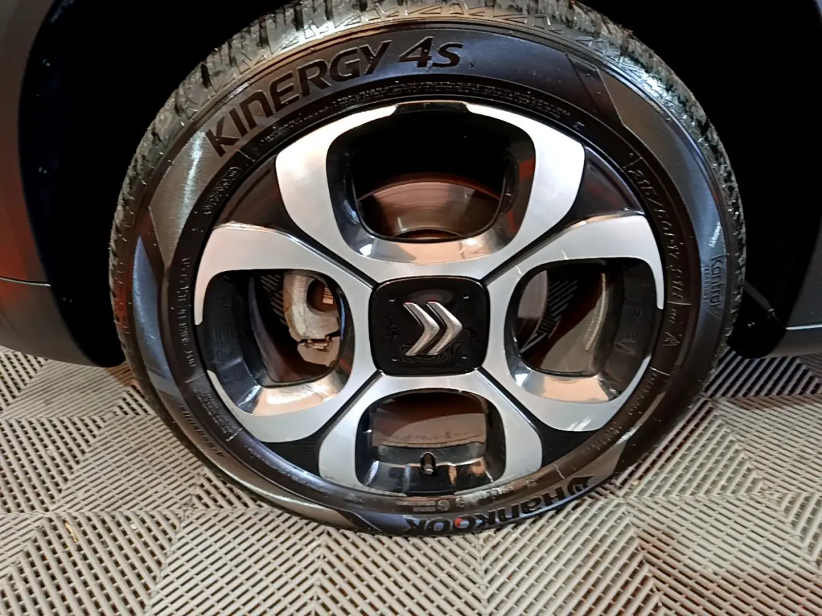 Gros plan sur la jante alliage noire et argentée avec logo Citroën, montée sur pneu Hankook d'un C3 Aircross noir.