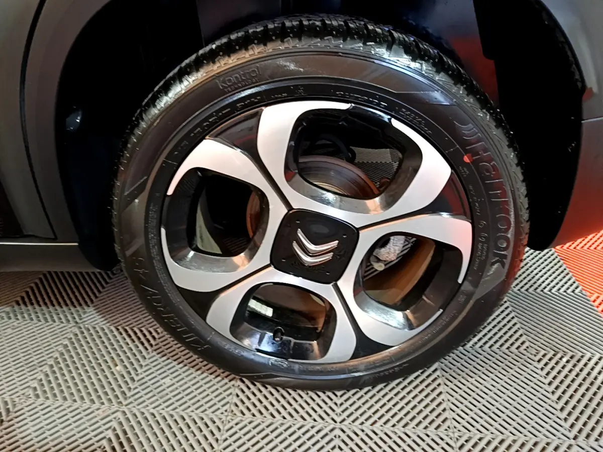 Gros plan sur la roue avant gauche noire du Citroën C3 Aircross avec jante alliage bicolore et logo Citroën central.