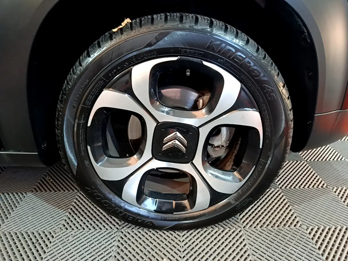 Gros plan sur la roue arrière droite noire du Citroën C3 Aircross PureTech 110 Shine, avec passage de roue et partie de la carrosserie visibles.