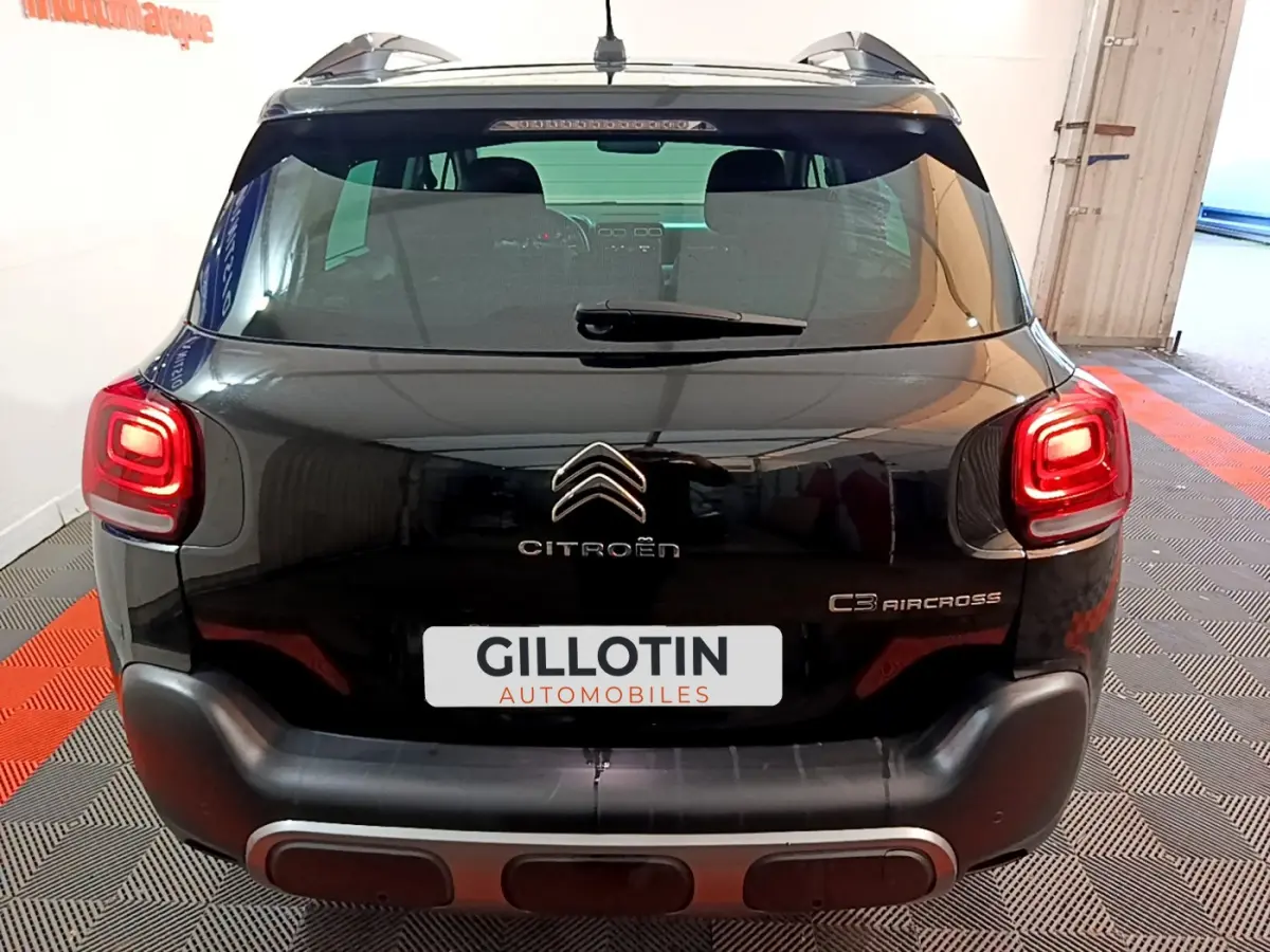 Vue arrière d'un Citroën C3 Aircross noir avec feux arrière allumés et logo distinctif sur un sol à damier.