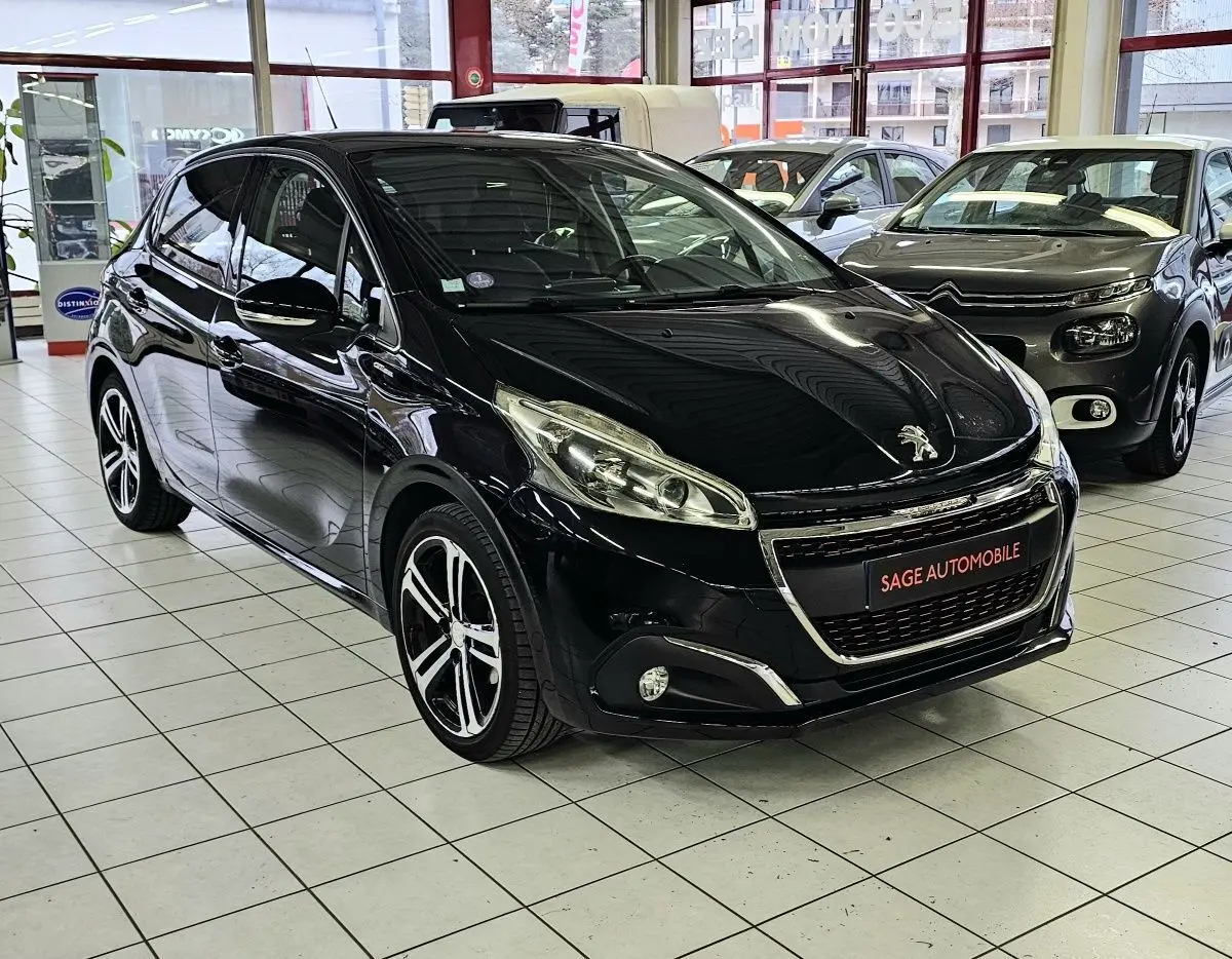 PEUGEOT 208 GT-LINE noir vue 3/4 avant droit en showroom avec jantes alliage et calandre chromée.