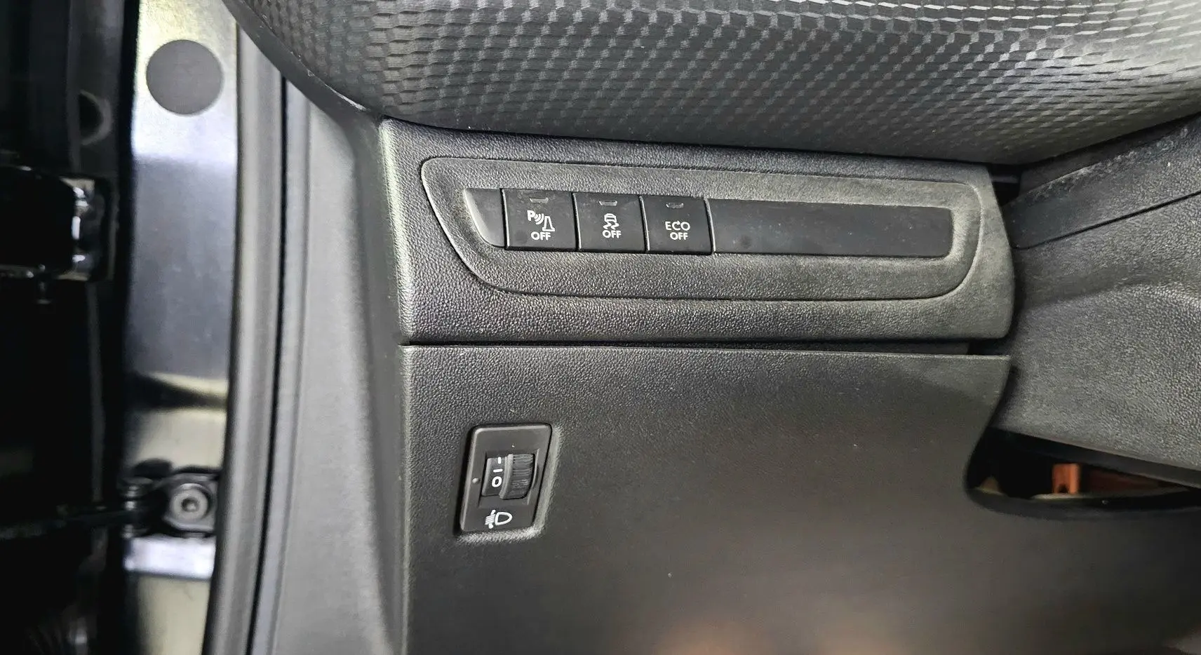 Détail des commandes côté gauche sous le siège conducteur de la Peugeot 208 GT-LINE noir, avec boutons de réglage et désactivation.