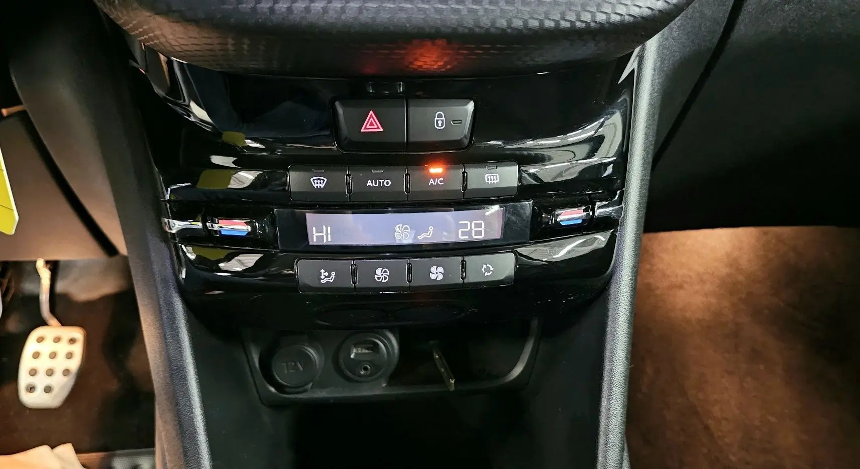 Gros plan sur la console centrale noire de la Peugeot 208 GT-LINE avec commandes de climatisation automatique et prise 12V.