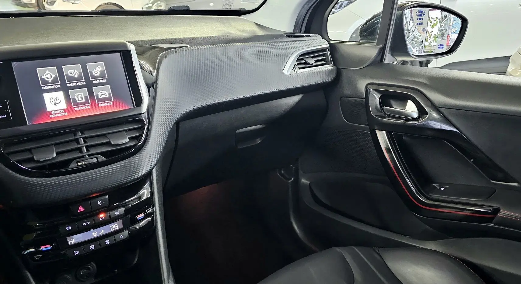 Intérieur avant droit de la Peugeot 208 GT-LINE noir, avec écran tactile et tableau de bord texturé gris.