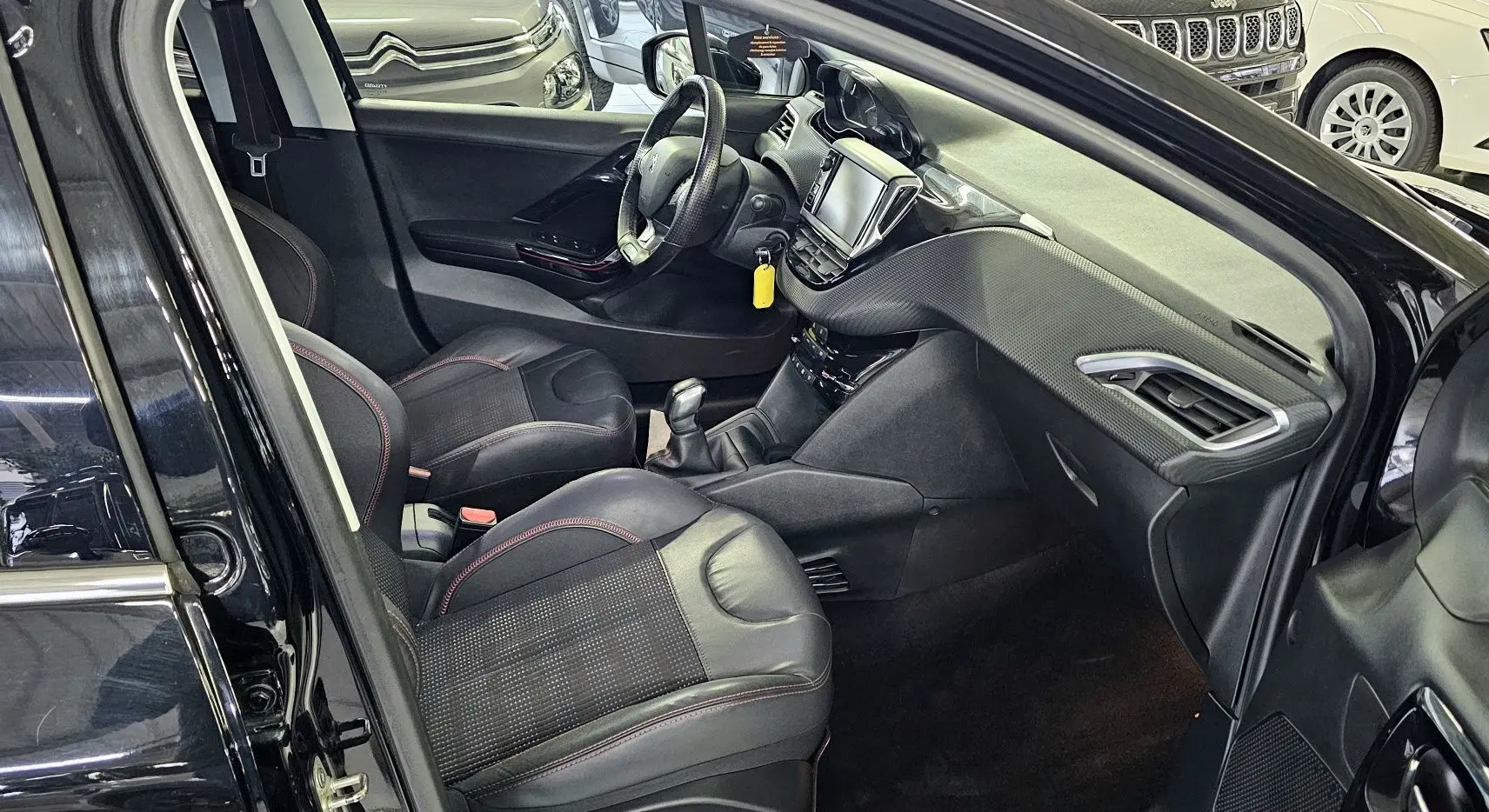 Intérieur noir de la Peugeot 208 GT-LINE 2015 vu côté conducteur, avec tableau de bord et sièges en cuir.