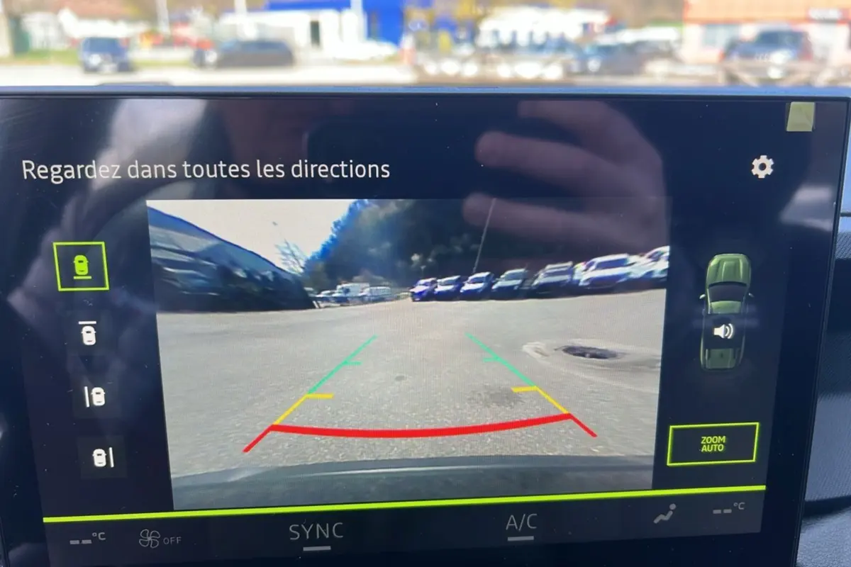 Écran de caméra multiview montrant la vue arrière du Dacia Bigster vert cèdre en stationnement.