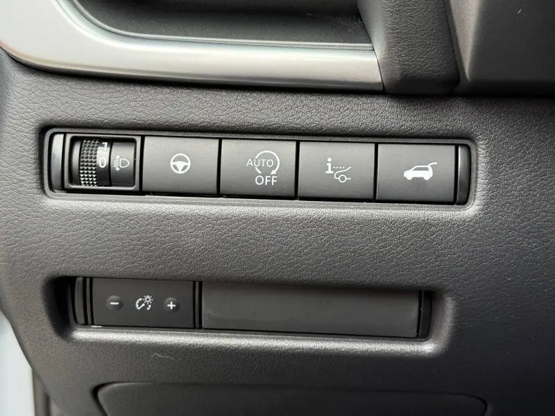 Détail des commandes noires sur tableau de bord du Nissan Qashqai 2025, boutons d'assistance et réglage éclairage.