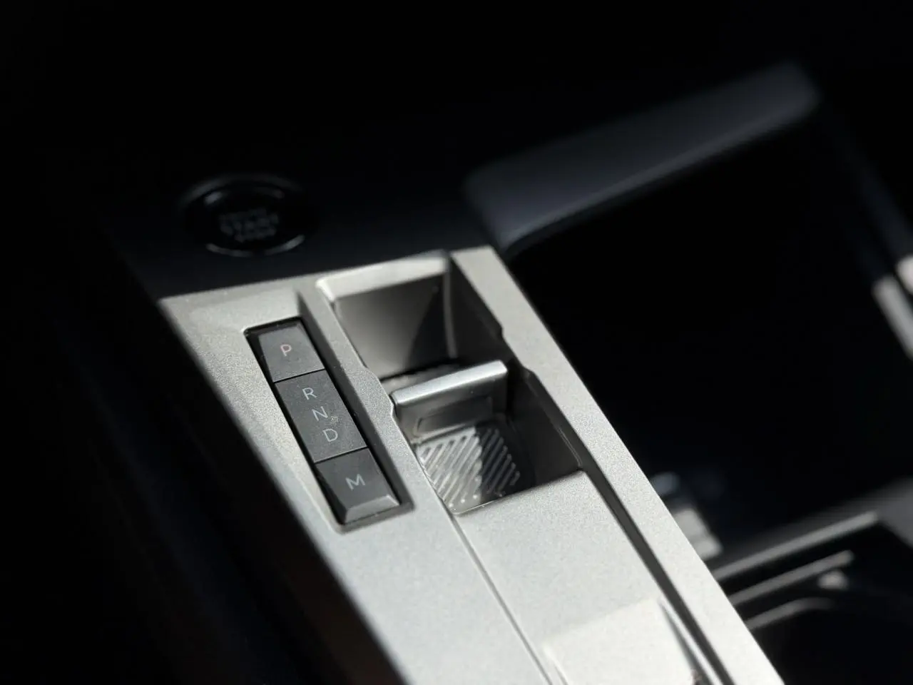 Gros plan sur la console centrale grise métallisée de la Peugeot 308 2025 avec boutons de boîte auto et rangement.