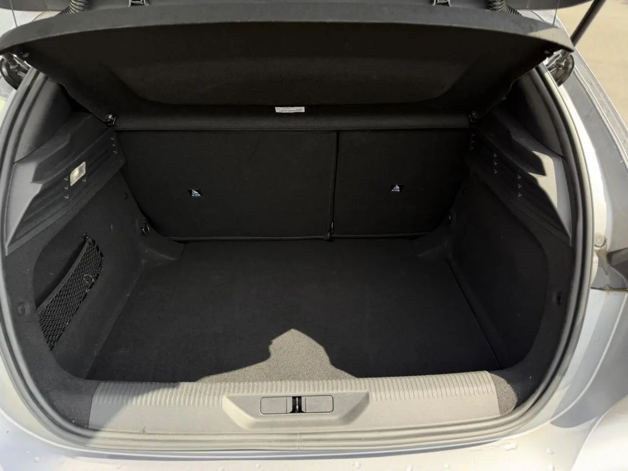 Coffre ouvert vu de l'arrière d'une Peugeot 308 gris Artense, montrant un espace de rangement vide et propre.