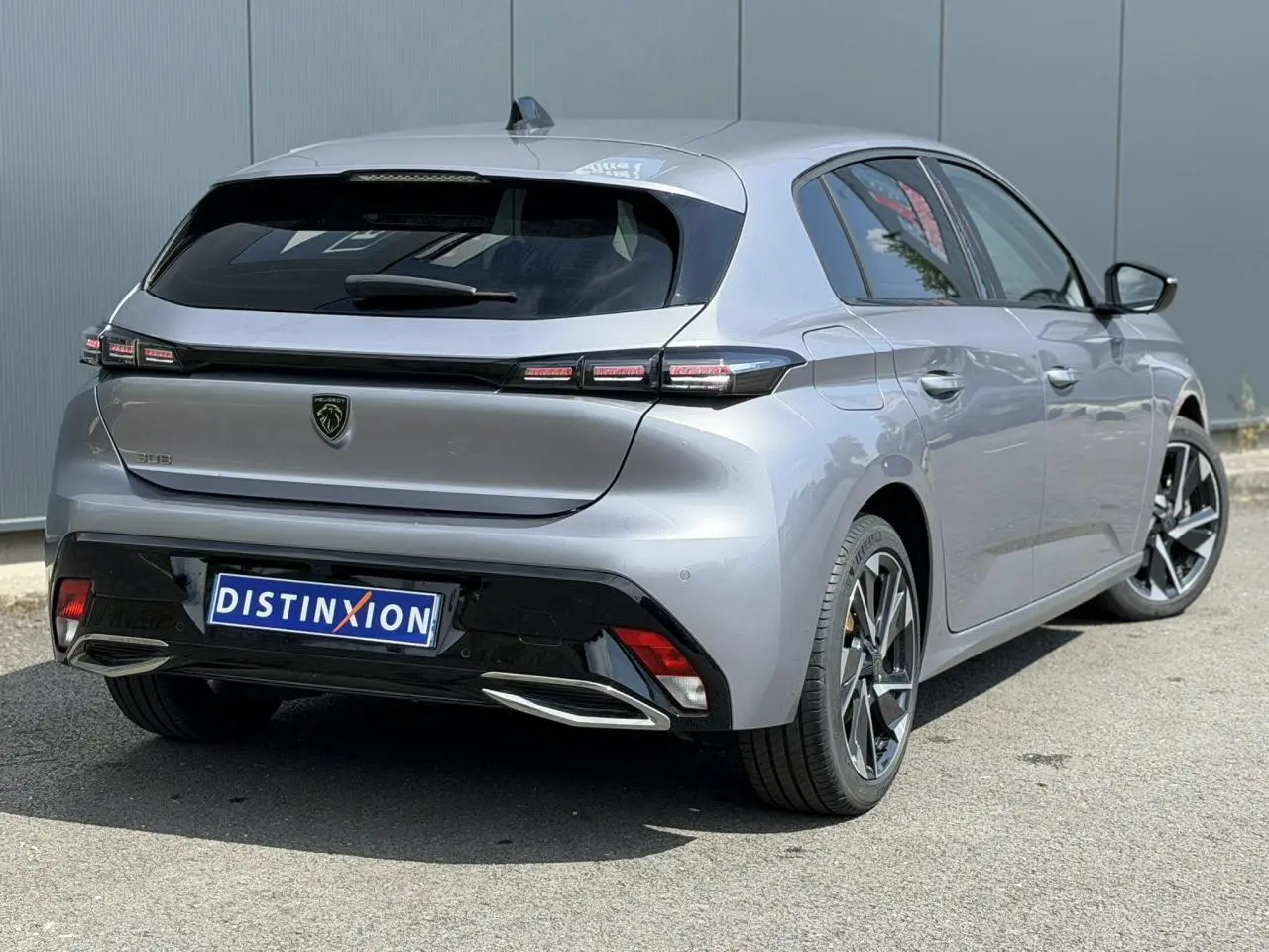 Vue 3/4 arrière droite de la Peugeot 308 gris Artense avec jantes alliage 17'' et bandeau noir brillant arrière.