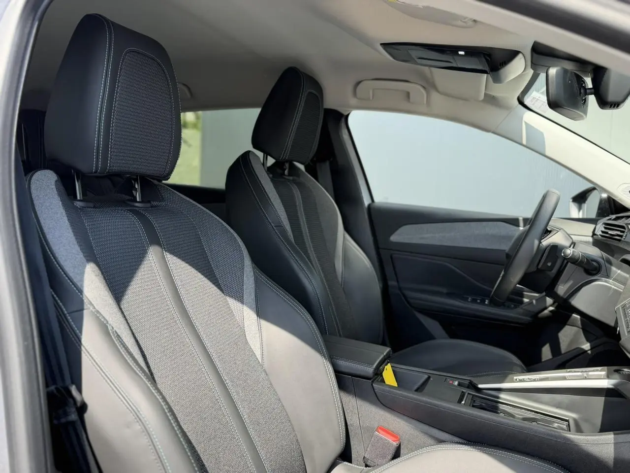 Vue intérieure de profil droit des sièges avant en tissu et cuir noir de la Peugeot 308 2025 finition Allure.