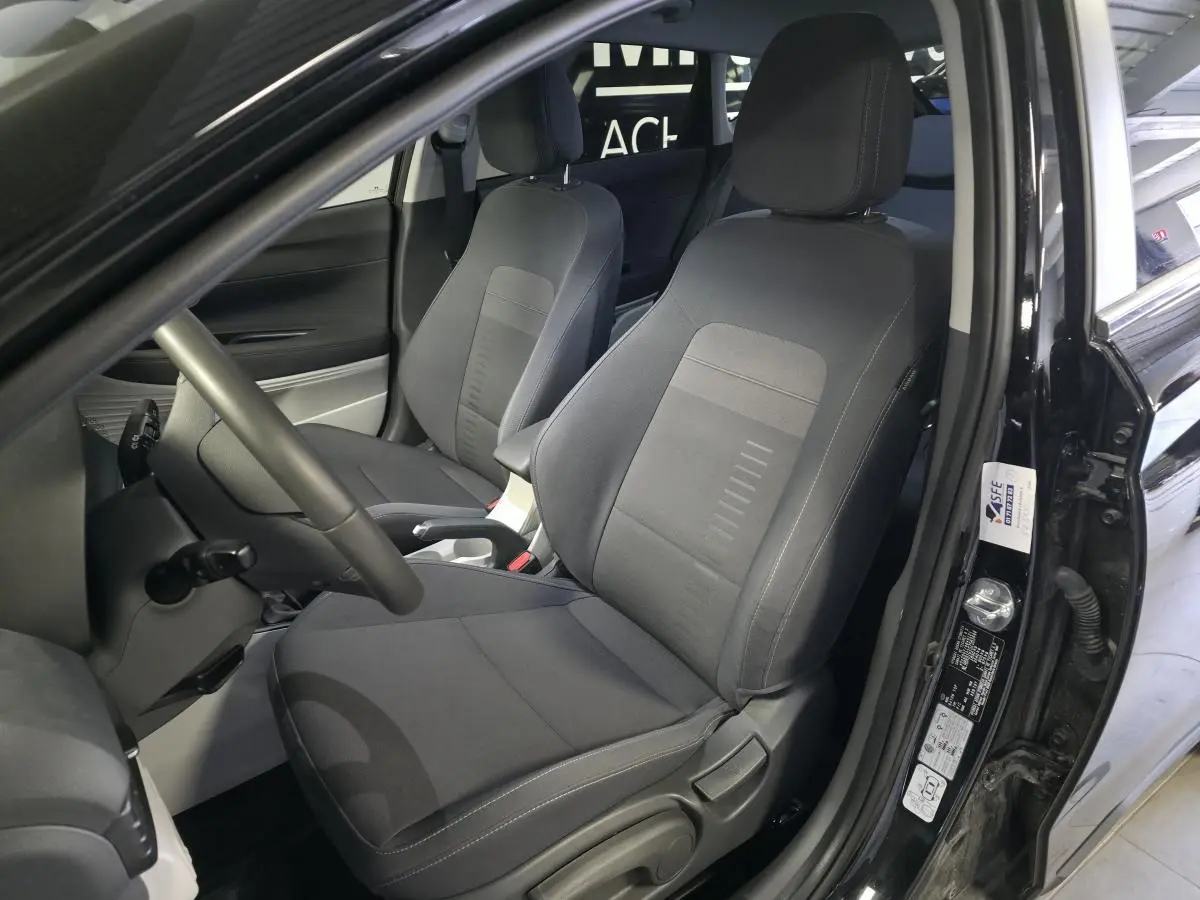 Intérieur avant du Hyundai Bayon noir, vue côté conducteur montrant sièges tissu gris et accoudoir central.