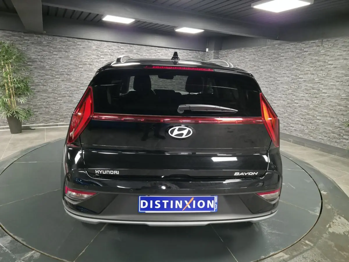 Vue arrière d'une Hyundai Bayon noire avec feux arrière LED et logo Hyundai bien visibles en intérieur showroom.