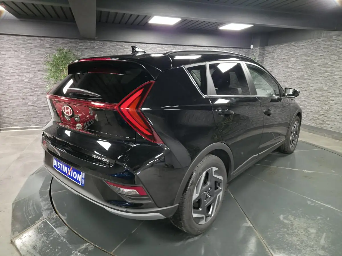 Vue 3/4 arrière droite d'une Hyundai Bayon noire avec feux arrière en forme de flèche et jantes alliage 17 pouces.