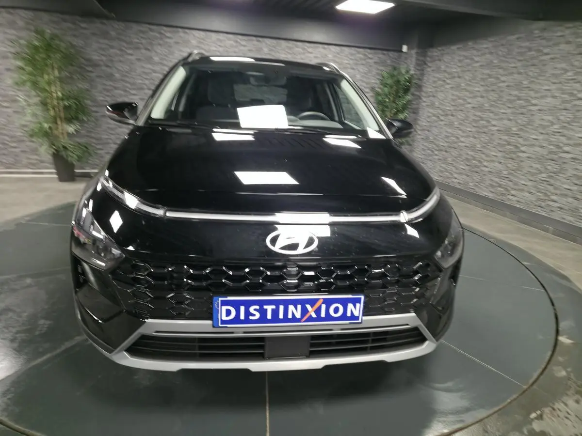 Vue avant d'un Hyundai Bayon noir 2025 avec calandre noire laquée et plaque Distinxion en intérieur showroom.