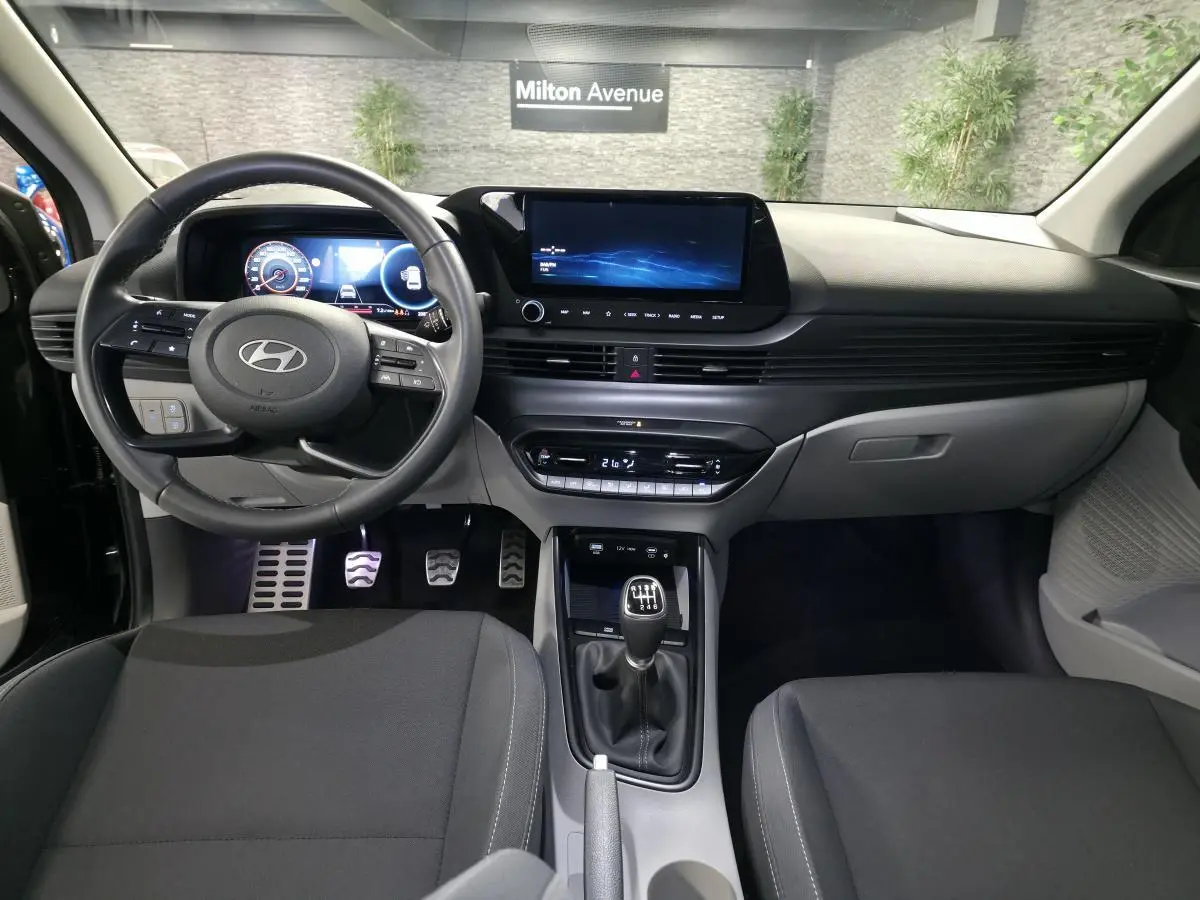 Intérieur bi-ton noir et gris clair de la Hyundai BAYON 2025, vue frontale sur tableau de bord et levier manuel.