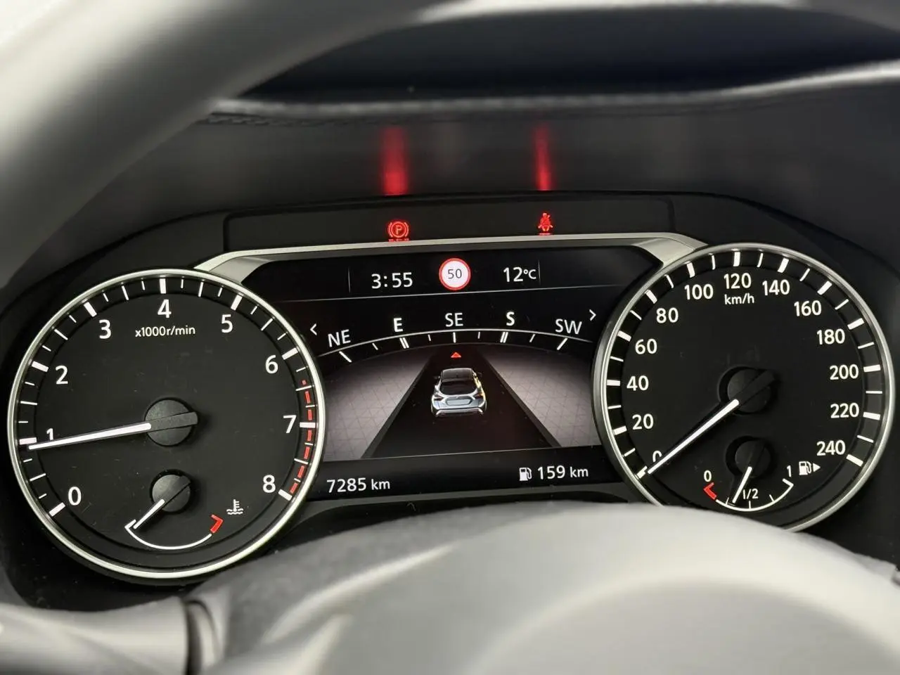 Tableau de bord du Nissan Juke 2025 essence, affichage numérique central et compte-tours à gauche.