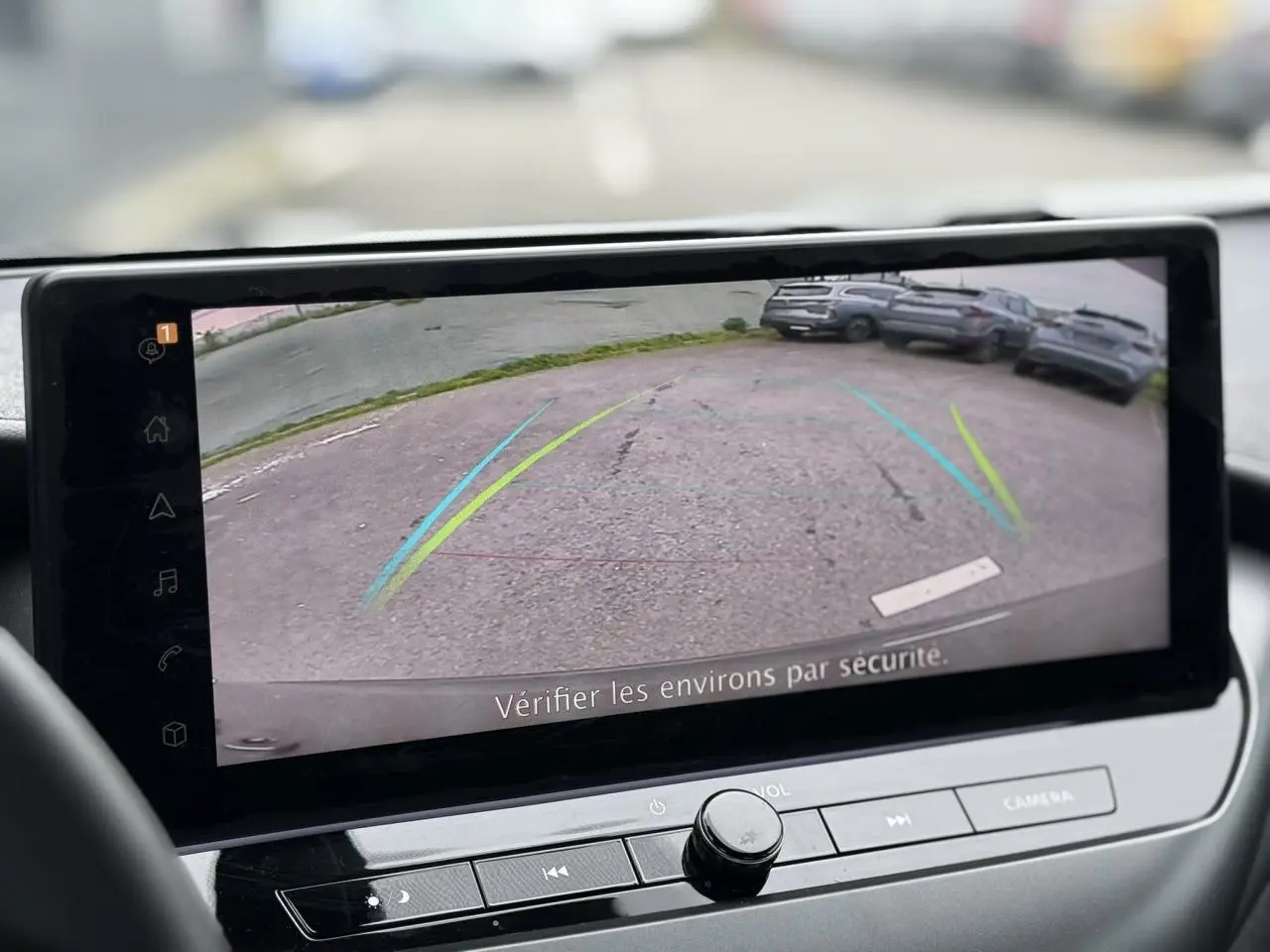 Écran tactile intérieur montrant la caméra de recul du Nissan Juke 2025, vue arrière sur un parking.