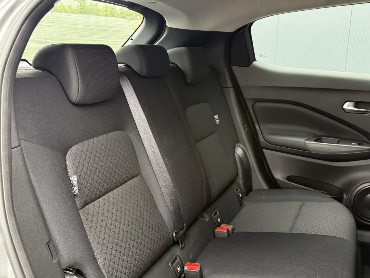 Vue latérale droite de la banquette arrière noire du Nissan Juke 2025 avec ceintures et appuie-têtes intégrés.