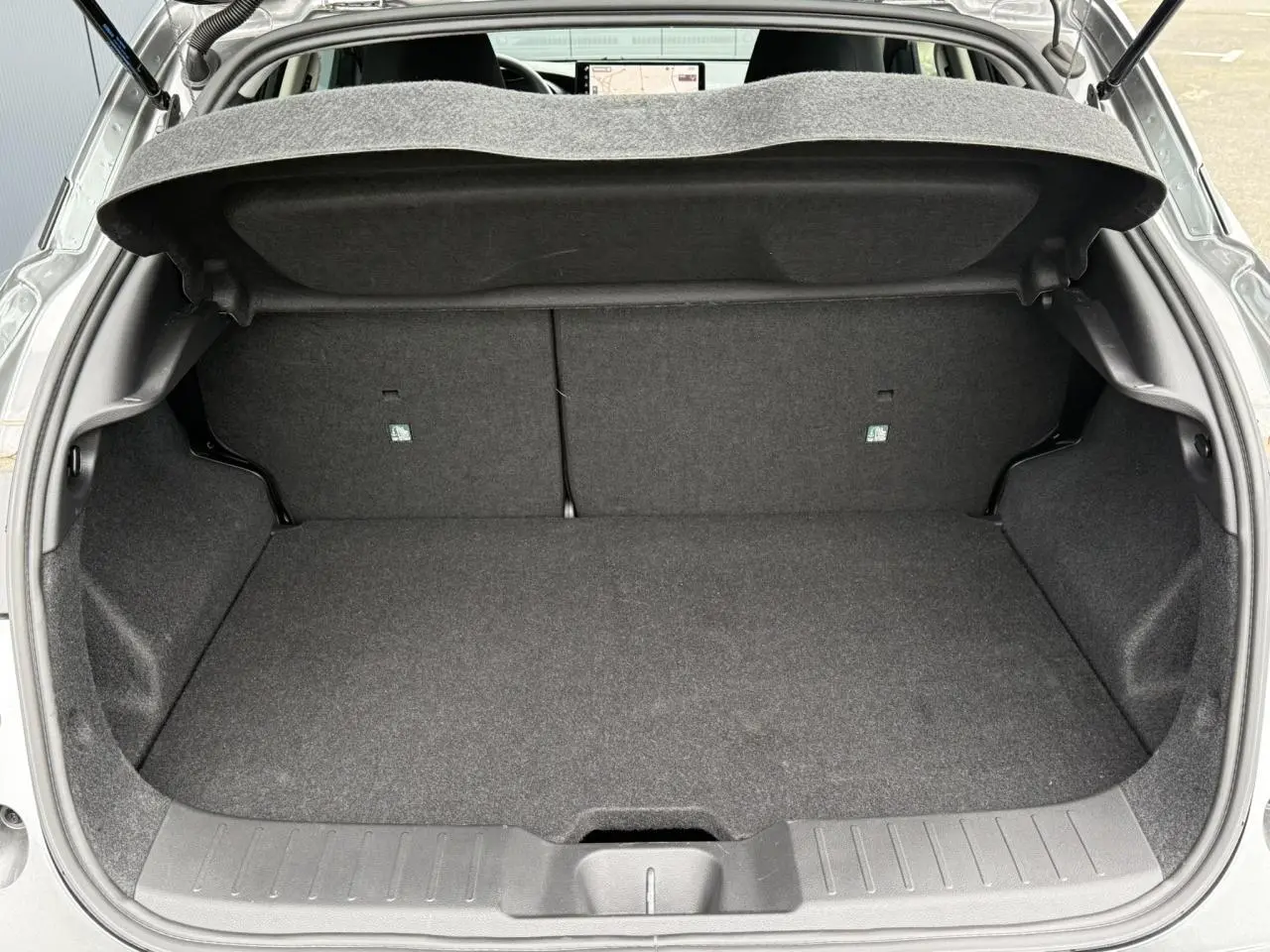 Vue arrière ouverte du coffre spacieux et propre d'un Nissan Juke 2025 gris foncé, sans chargement visible.