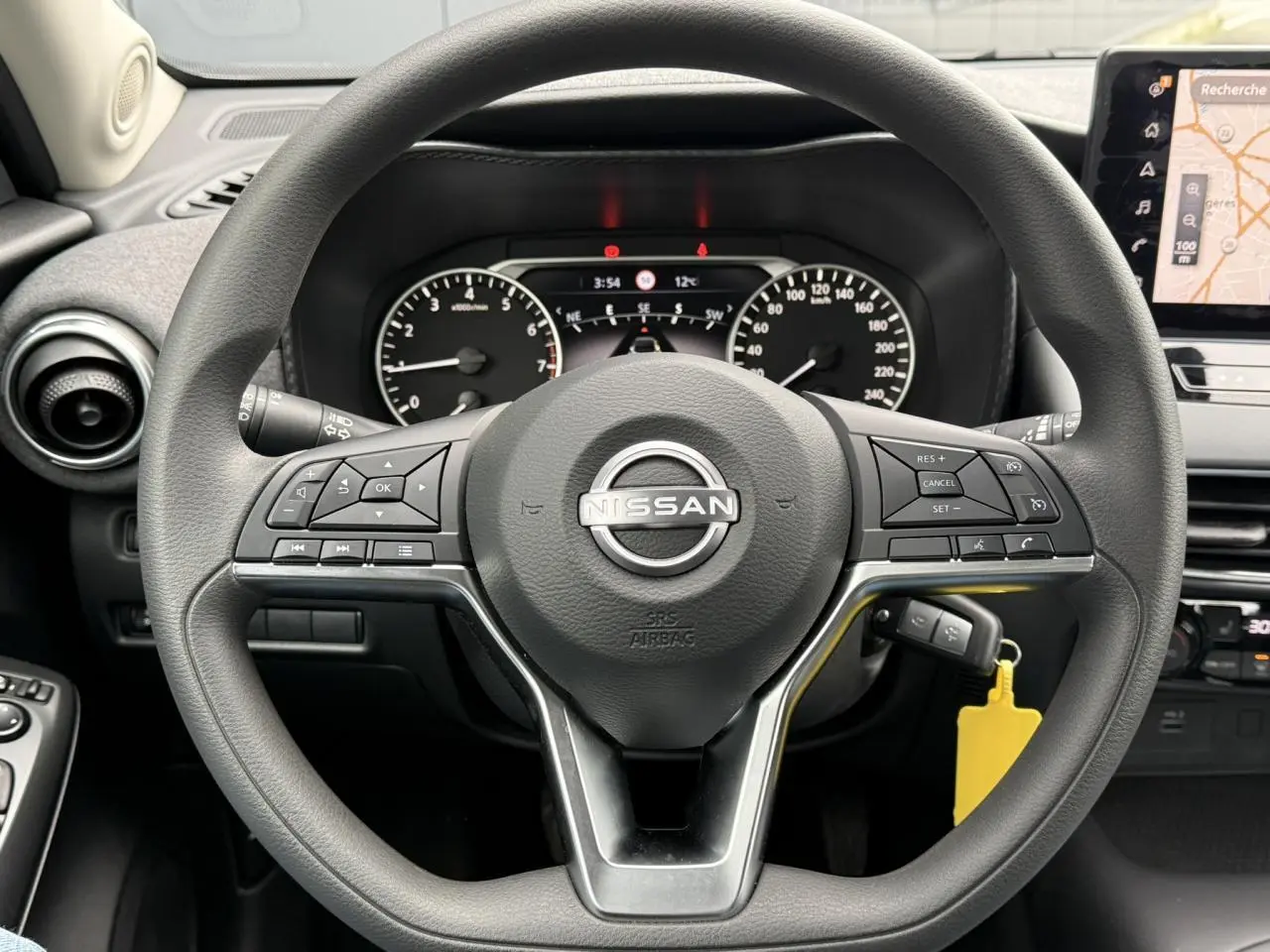 Vue centrée sur le volant noir du Nissan Juke 2025 avec commandes intégrées et écran GPS tactile visible à droite.