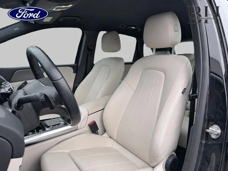 Vue intérieure côté conducteur d'une Mercedes Classe B 250 e noire avec sièges avant en similicuir beige ARTICO.