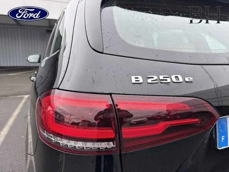 Gros plan sur l'arrière droit noir cosmos métallisé d'une Mercedes Classe B 250 e avec feux rouges allongés et logo B 250 e.