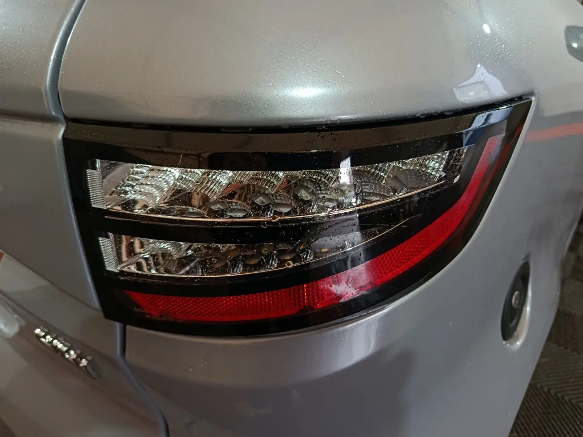 Gros plan sur le feu arrière droit gris clair de l'AIXAM AMBITION 0.5 CITY PACK 2026 avec détails lumineux et carrosserie lisse.