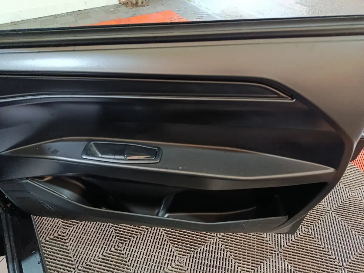 Intérieur montrant la porte côté conducteur de l'AIXAM Ambition 0.5 City Pack gris clair, avec poignée et rangement intégré.