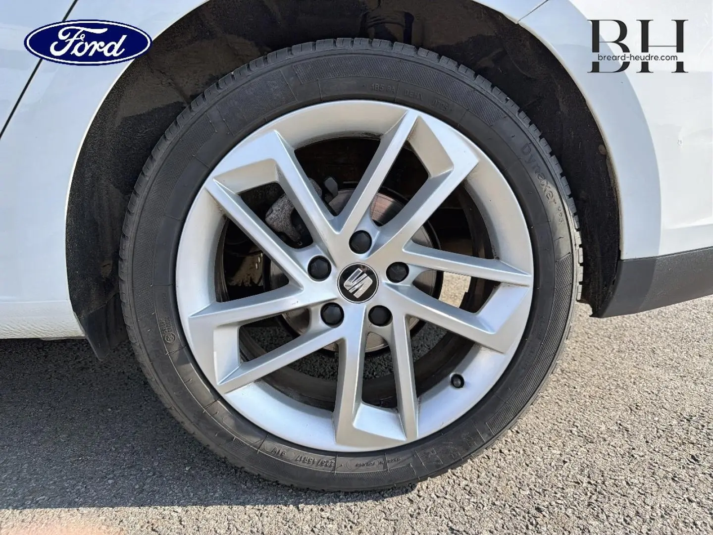 Gros plan sur la roue avant droite d'une SEAT LEON ST blanche avec jante alliage à 5 branches doubles.