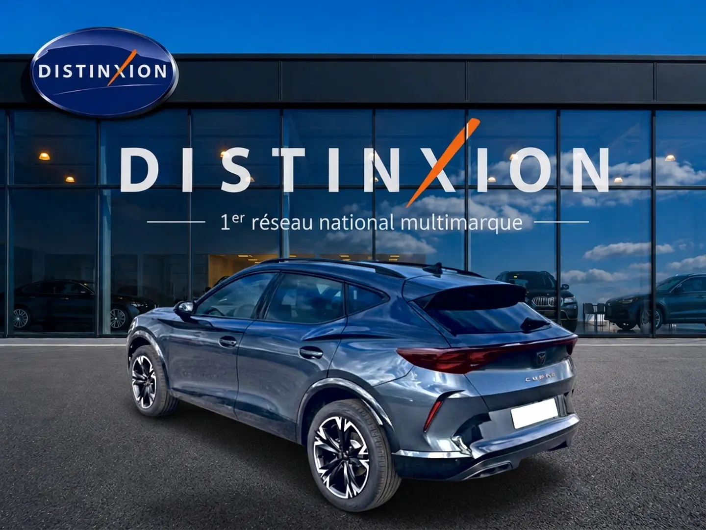 Vue 3/4 arrière droite d'un CUPRA Formentor gris magnétique avec jantes noires et toit plongeant devant un showroom Distinxion.