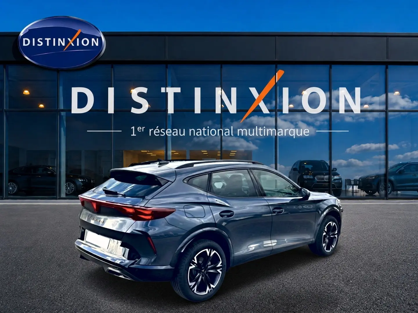Vue 3/4 arrière droite d'un CUPRA Formentor gris magnétique avec jantes 18 pouces et diffuseur arrière noir devant un showroom Distinxion.