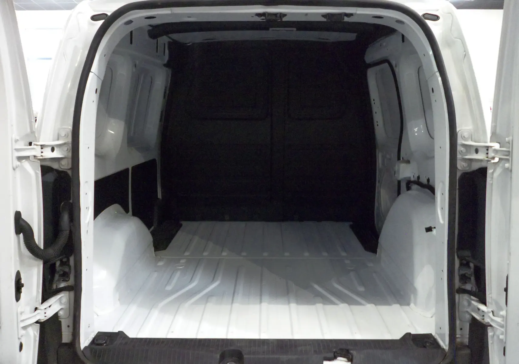 Vue arrière ouverte du Renault Kangoo Van blanc minéral, montrant l'espace de chargement vide et les portes battantes ouvertes.