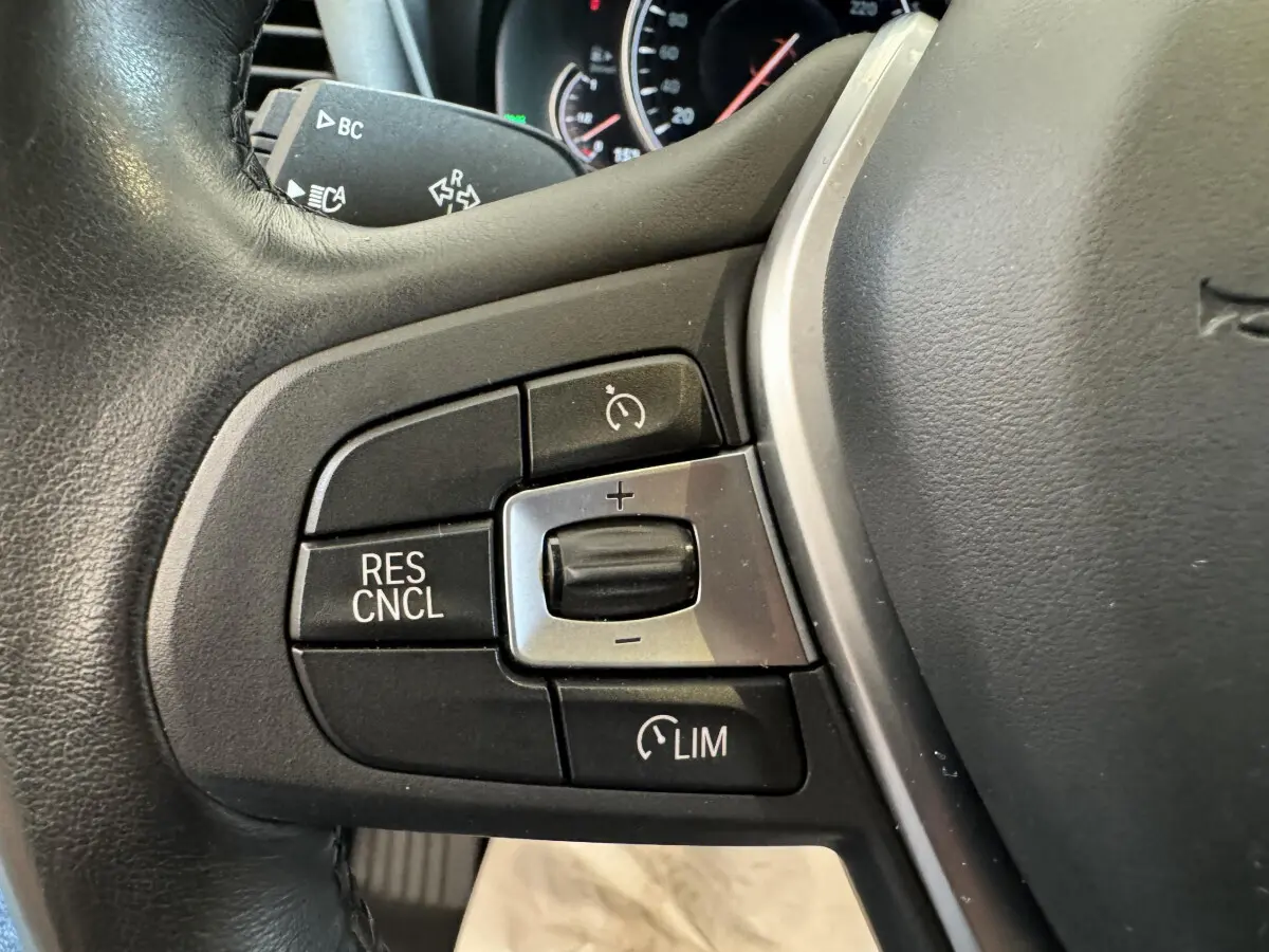 Gros plan sur les commandes du régulateur de vitesse au volant cuir du BMW X3 gris foncé, version Luxury 2018.