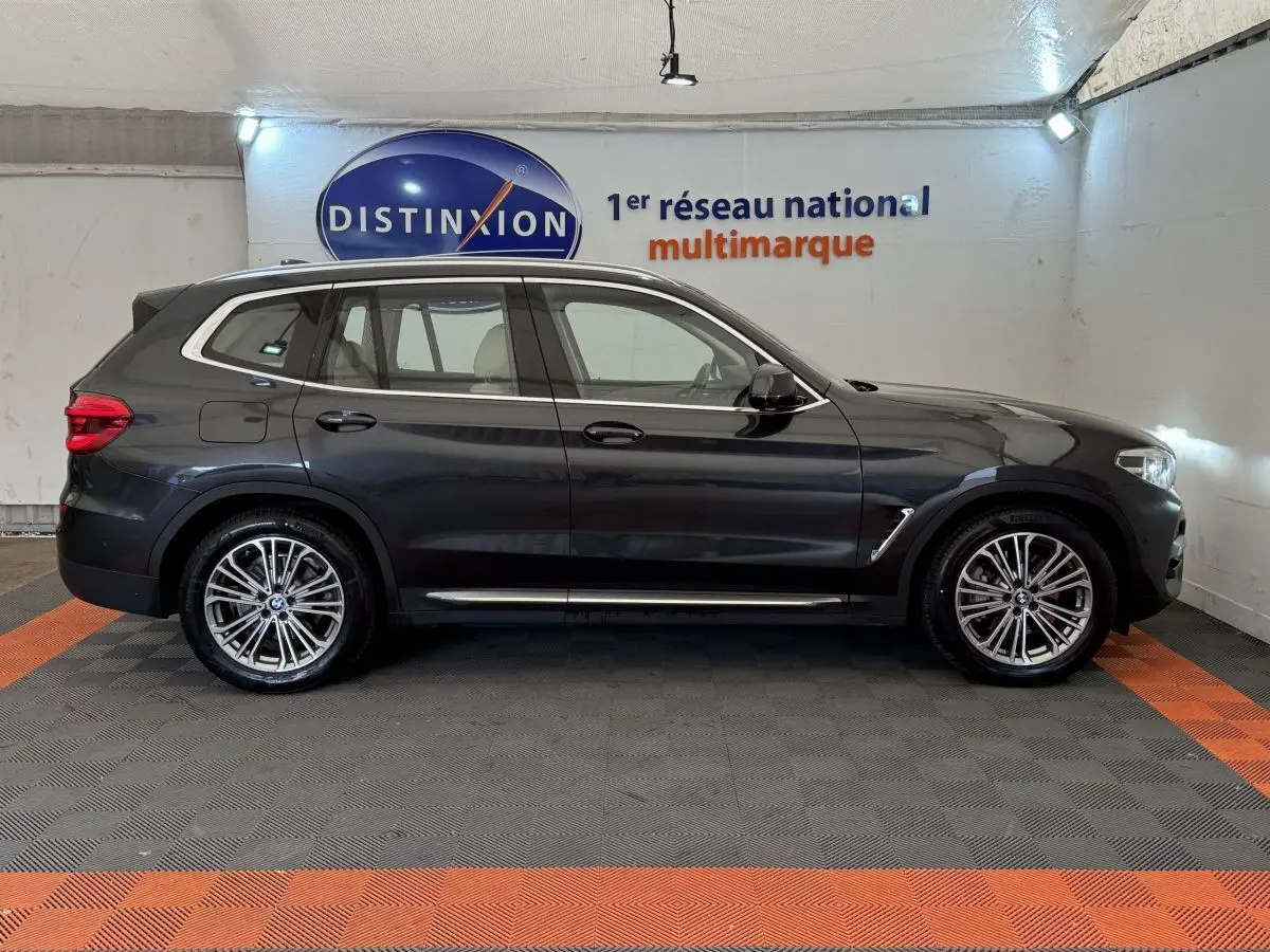 BMW X3 xDrive30d gris foncé vu de profil côté gauche, avec jantes alliage et toit noir dans un showroom.