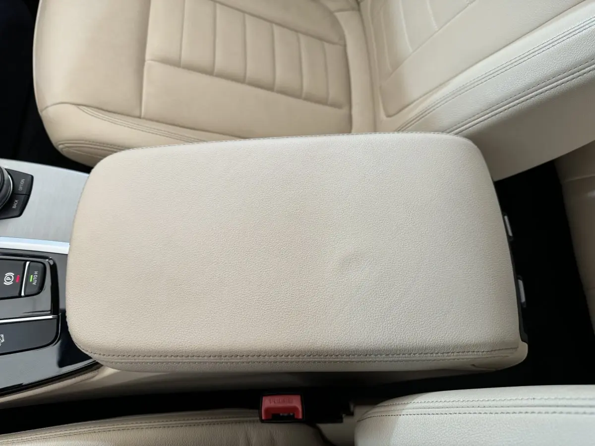 Gros plan sur l'accoudoir central beige et les sièges en cuir clair de l'intérieur du BMW X3 xDrive30d 2018.
