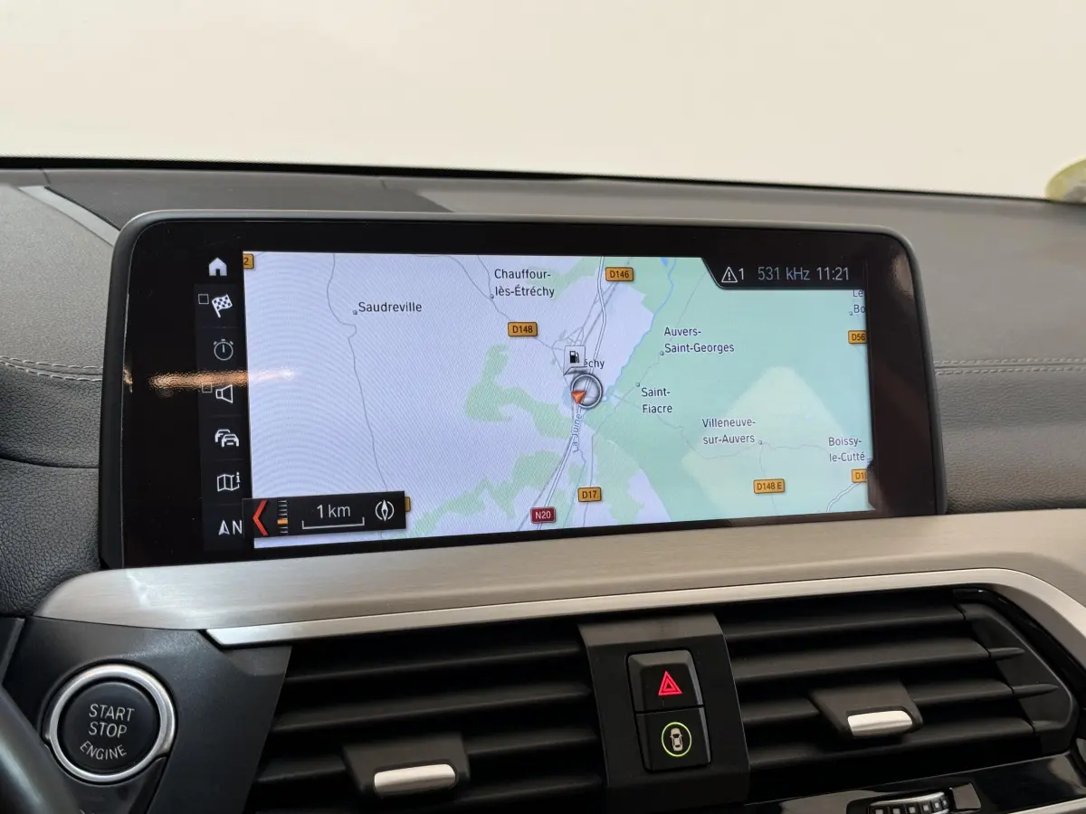 Vue rapprochée de l'écran tactile 10,3 pouces du tableau de bord du BMW X3 gris foncé affichant la navigation GPS.