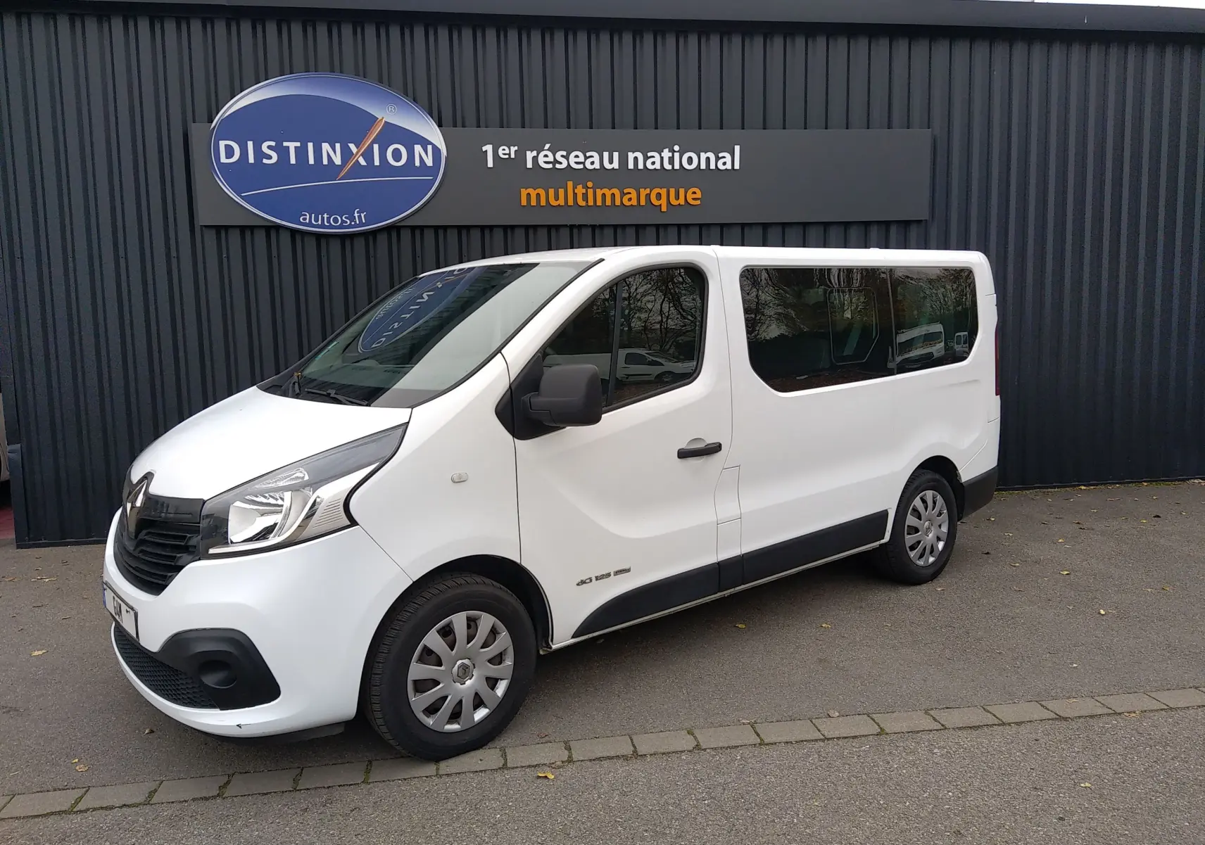 Renault Trafic Microbus blanc en vue 3/4 avant droit, avec vitres teintées et jantes acier.