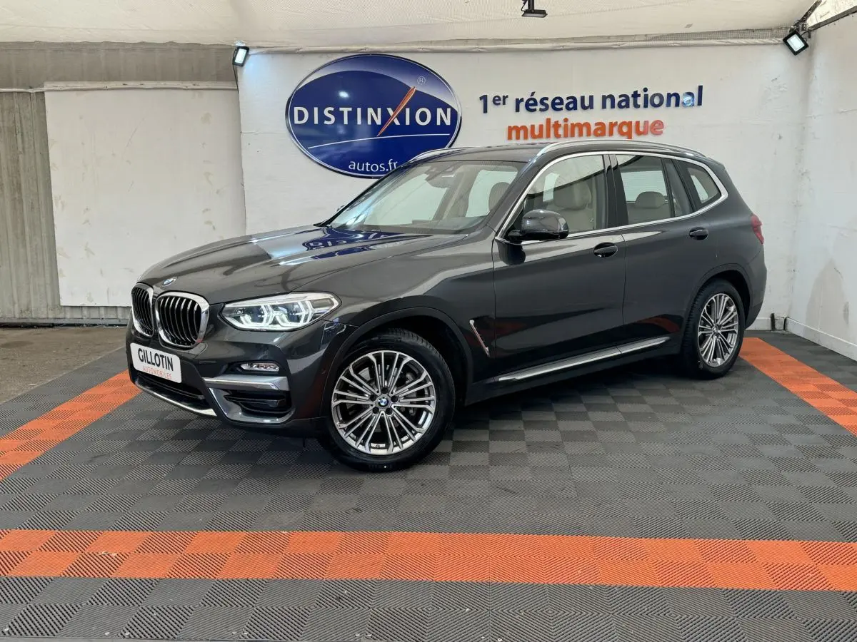 BMW X3 xDrive30d gris foncé vu en 3/4 avant droit dans un showroom avec éclairage intérieur.