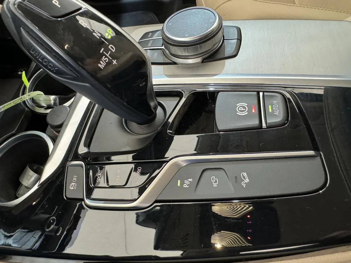 Gros plan sur la console centrale noire brillante du BMW X3 xDrive30d 2018 avec levier de vitesses automatique et commandes de conduite.