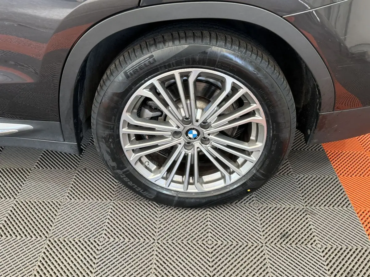 Gros plan sur la roue avant droite d’un BMW X3 gris foncé avec jante alliage multi-branches et pneu Pirelli.