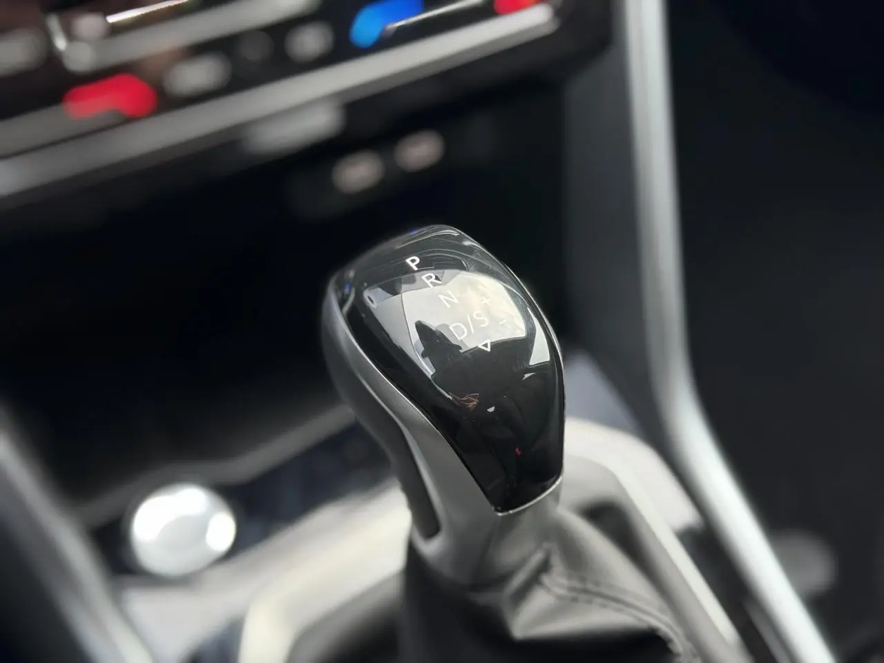 Le levier de vitesses automatique noir brillant du Volkswagen T-Roc 1.5 TSI 150 DSG Life 30 Years, intérieur moderne.