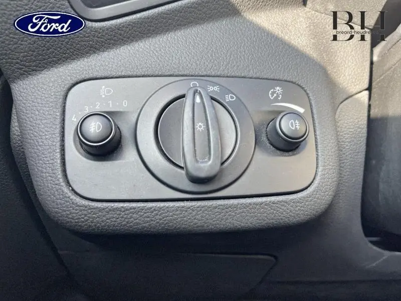 Gros plan sur le bouton de commande des phares du Ford Kuga blanc Glacier, côté gauche du tableau de bord.