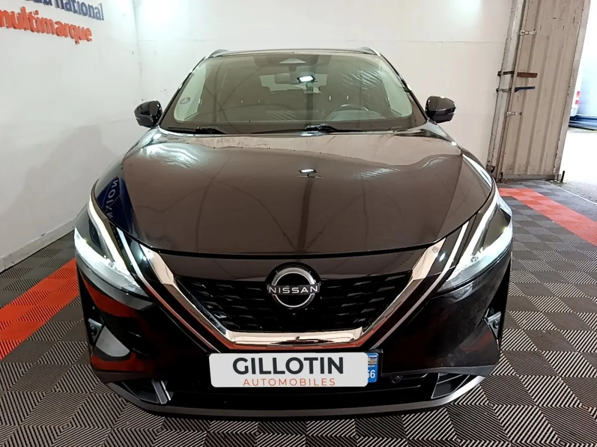 Vue avant d’un Nissan Qashqai e-Power noir, avec calandre chromée et phares LED allumés dans un showroom.
