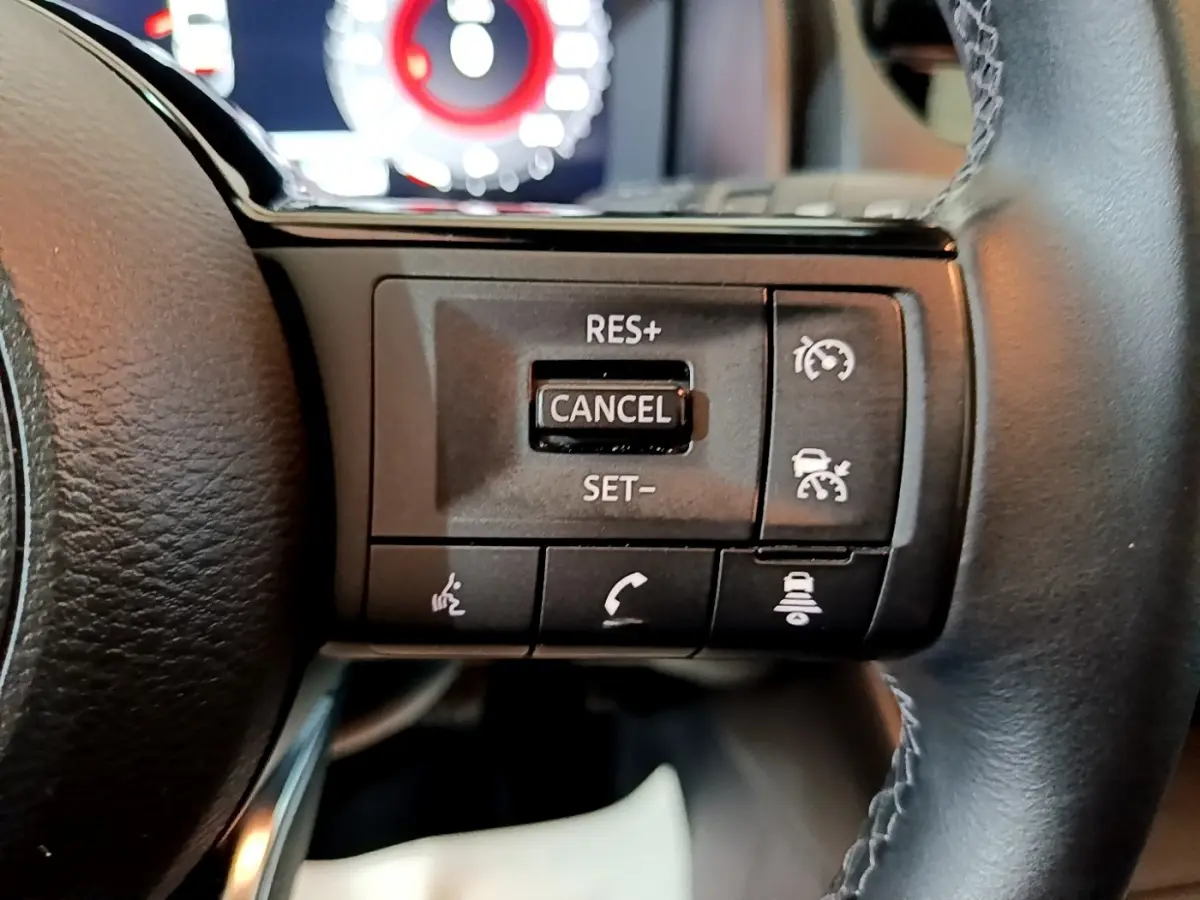 Gros plan sur les commandes multifonctions en cuir et alu du volant noir du Nissan Qashqai e-Power 2023.