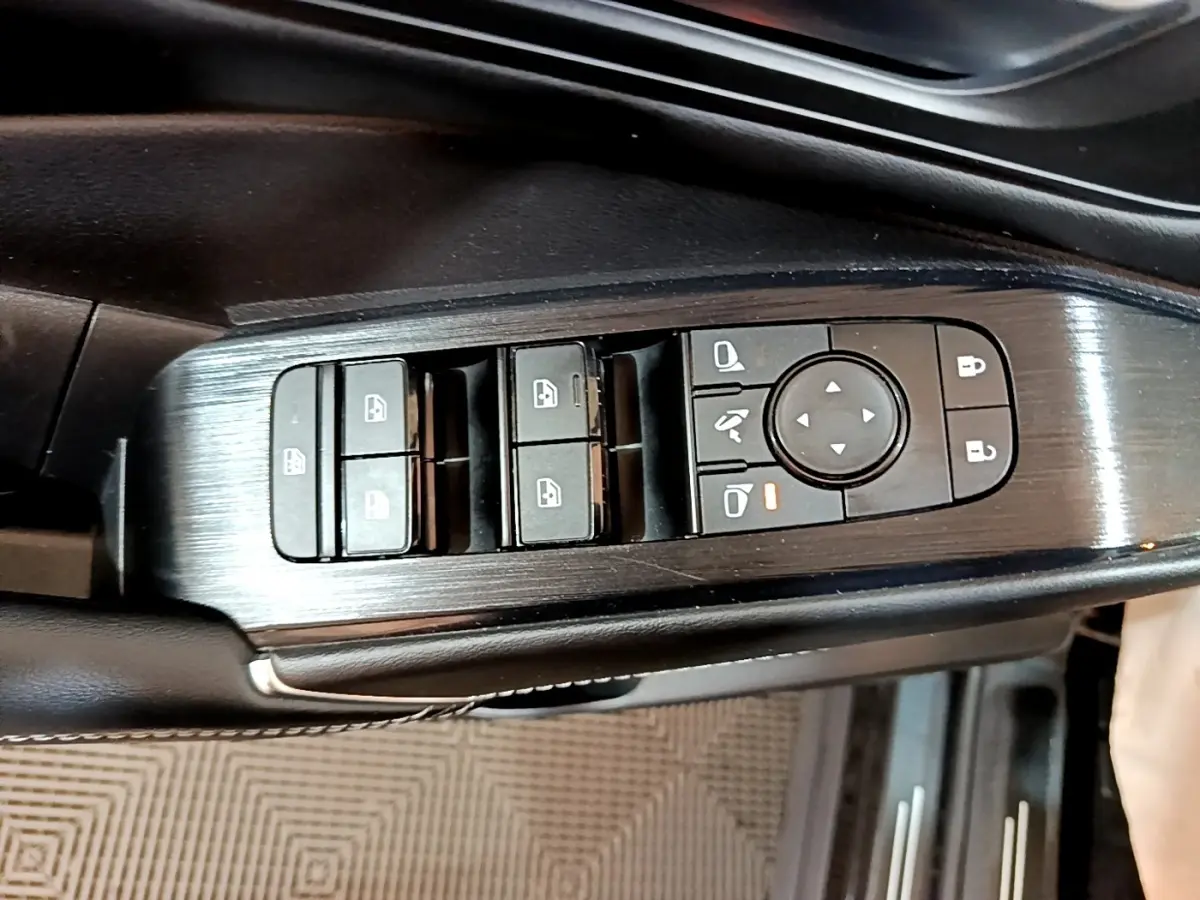 Gros plan sur la commande des vitres et rétroviseurs côté gauche du Nissan Qashqai e-Power noir, finition alu brossé.