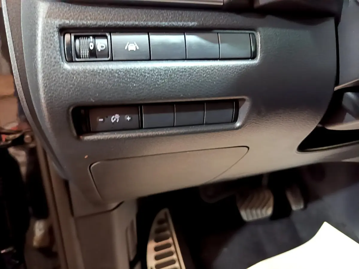 Détail du tableau de bord côté gauche avec commandes d'aide à la conduite et pédales visibles dans un Nissan Qashqai noir.