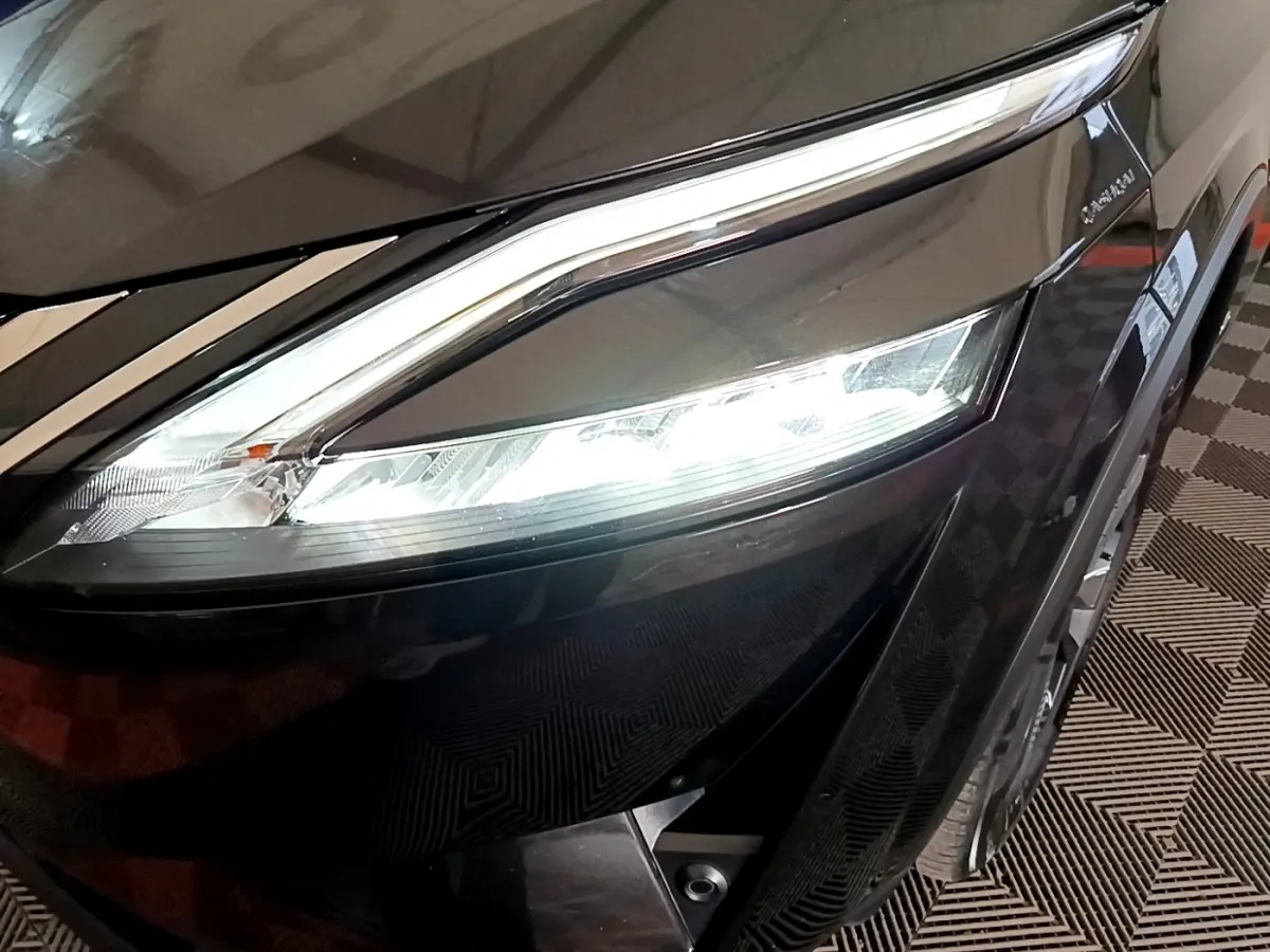 Gros plan sur le phare avant gauche allumé du Nissan Qashqai e-Power noir, soulignant ses lignes modernes et LED.