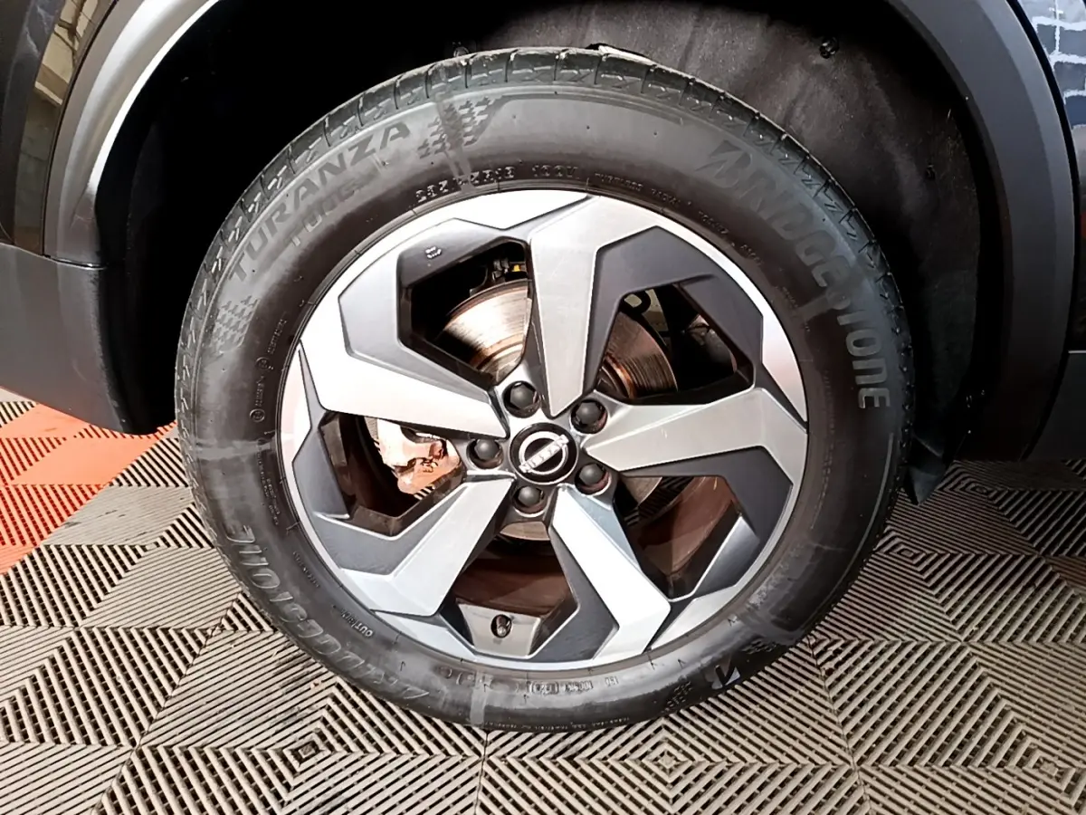 Gros plan sur la roue avant droite noire du Nissan Qashqai e-Power 190 N-Connecta avec jante alu bicolore.