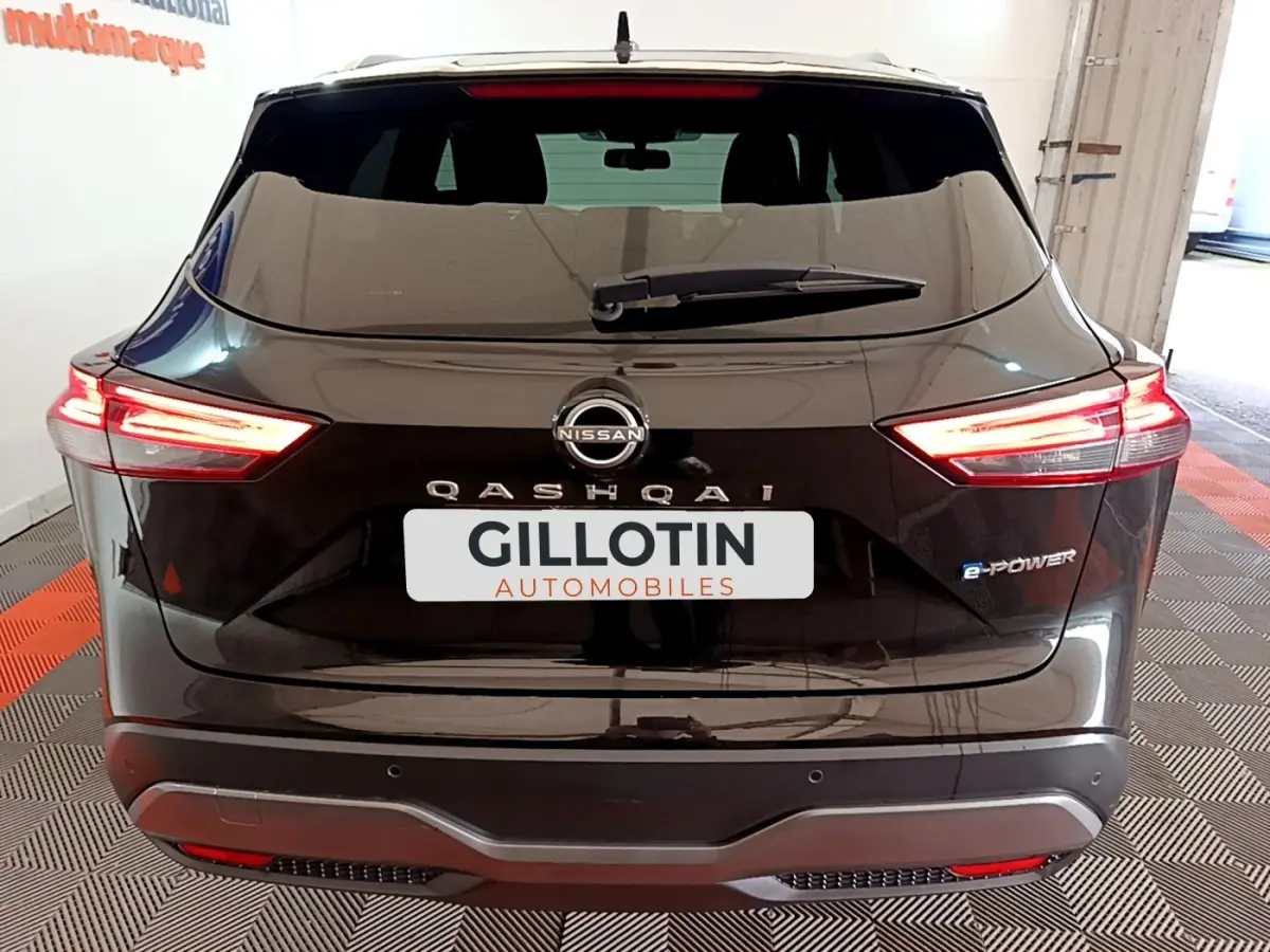 Vue arrière d'un Nissan Qashqai e-Power noir avec feux LED allumés et logo e-Power visible à droite.